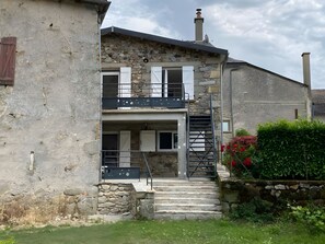 A two-story building with a stone facade, a balcony, and a staircase leading to the upper floor.