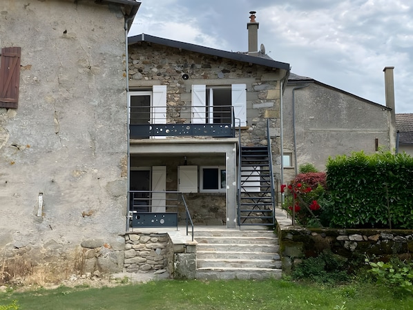 A two-story building with a stone facade, a balcony, and a staircase leading to the upper floor.