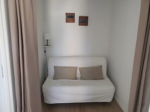Een eenpersoonsbed met twee kussens, een bedlampje en twee foto's aan de muur.