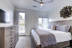 A bedroom with a bed, a dresser, a ceiling fan, and a large window. - Poolside, Dog Friendly Home - 3 King Master En-Suites & Bunk Room (St. George)