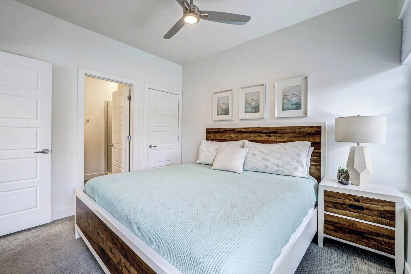 Une chambre à coucher avec un lit, une table de chevet, une lampe et un ventilateur de plafond.