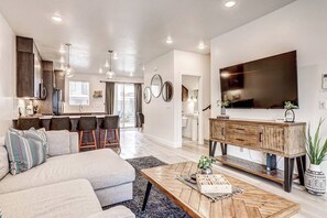 A modern living space with a sofa, coffee table, and bar stools. - Poolside, Dog Friendly Home - 3 King Master En-Suites & Bunk Room (St. George)