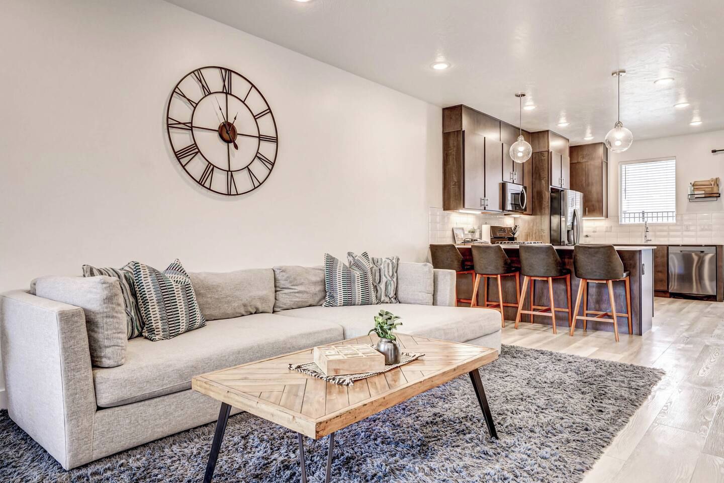 Een moderne woonkamer met een bank, salontafel en een grote wandklok.