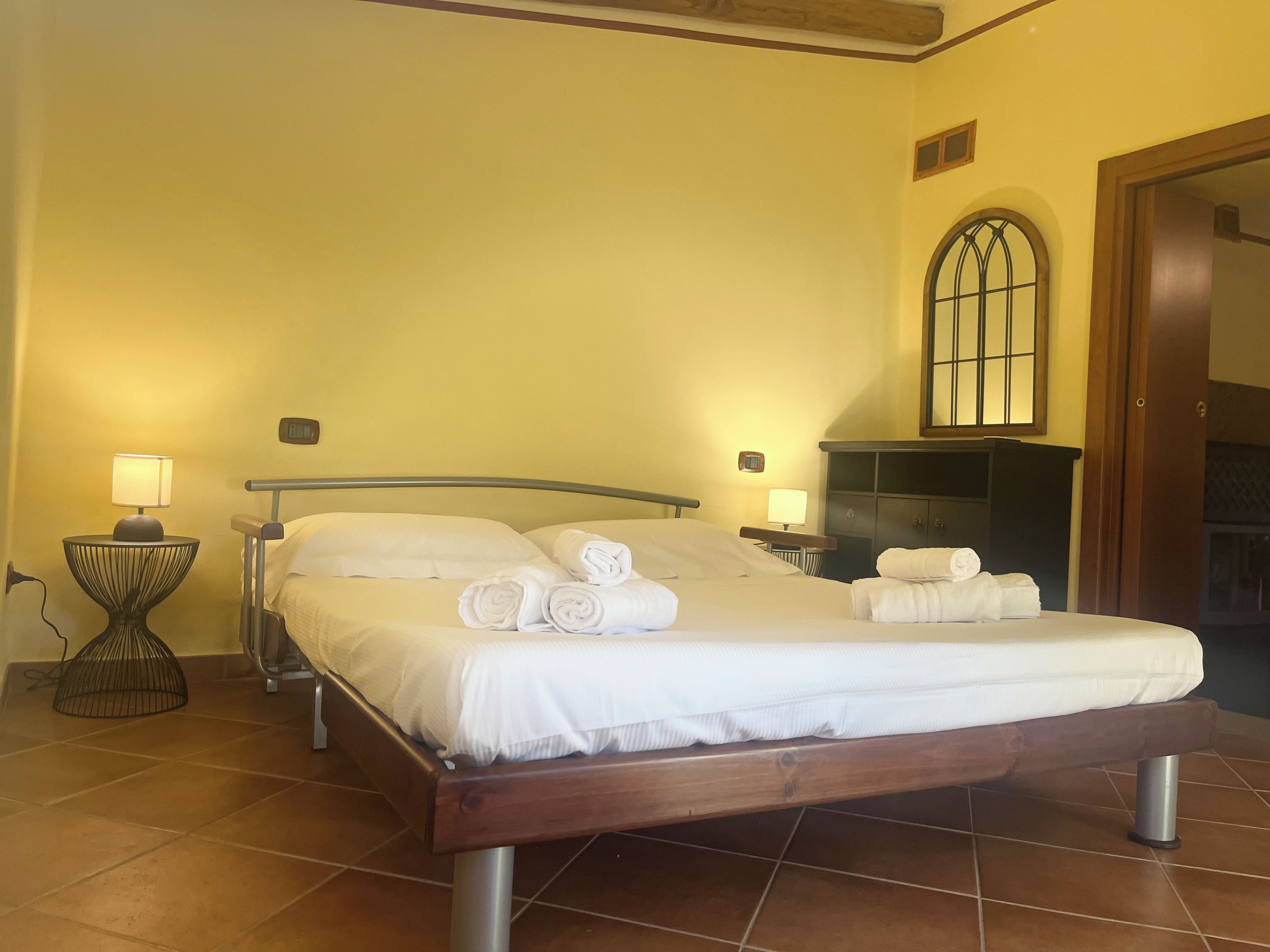Ein Hotelzimmer mit einem Bett, zwei Nachttischlampen, einem kleinen Tisch und einem Kleiderschrank.