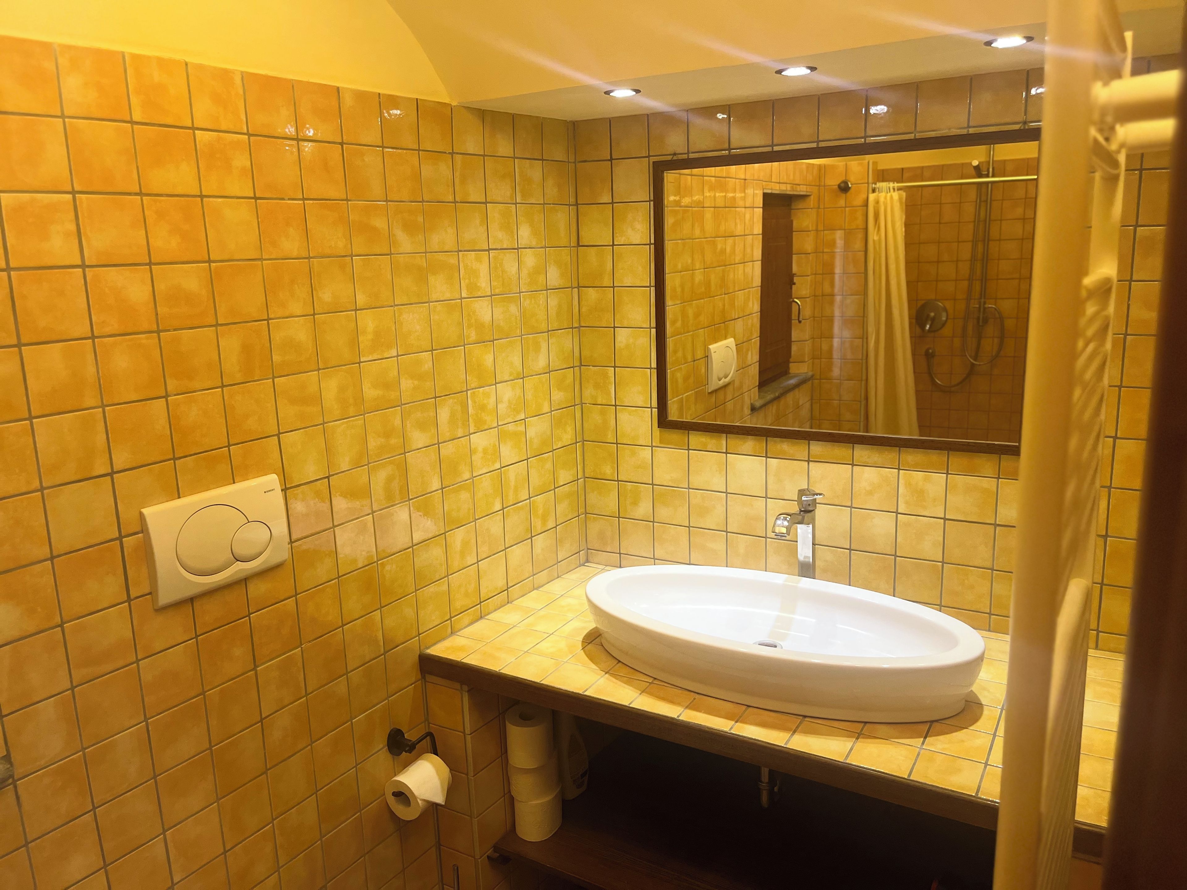 Une salle de bain avec un lavabo blanc, un miroir et un rideau de douche.