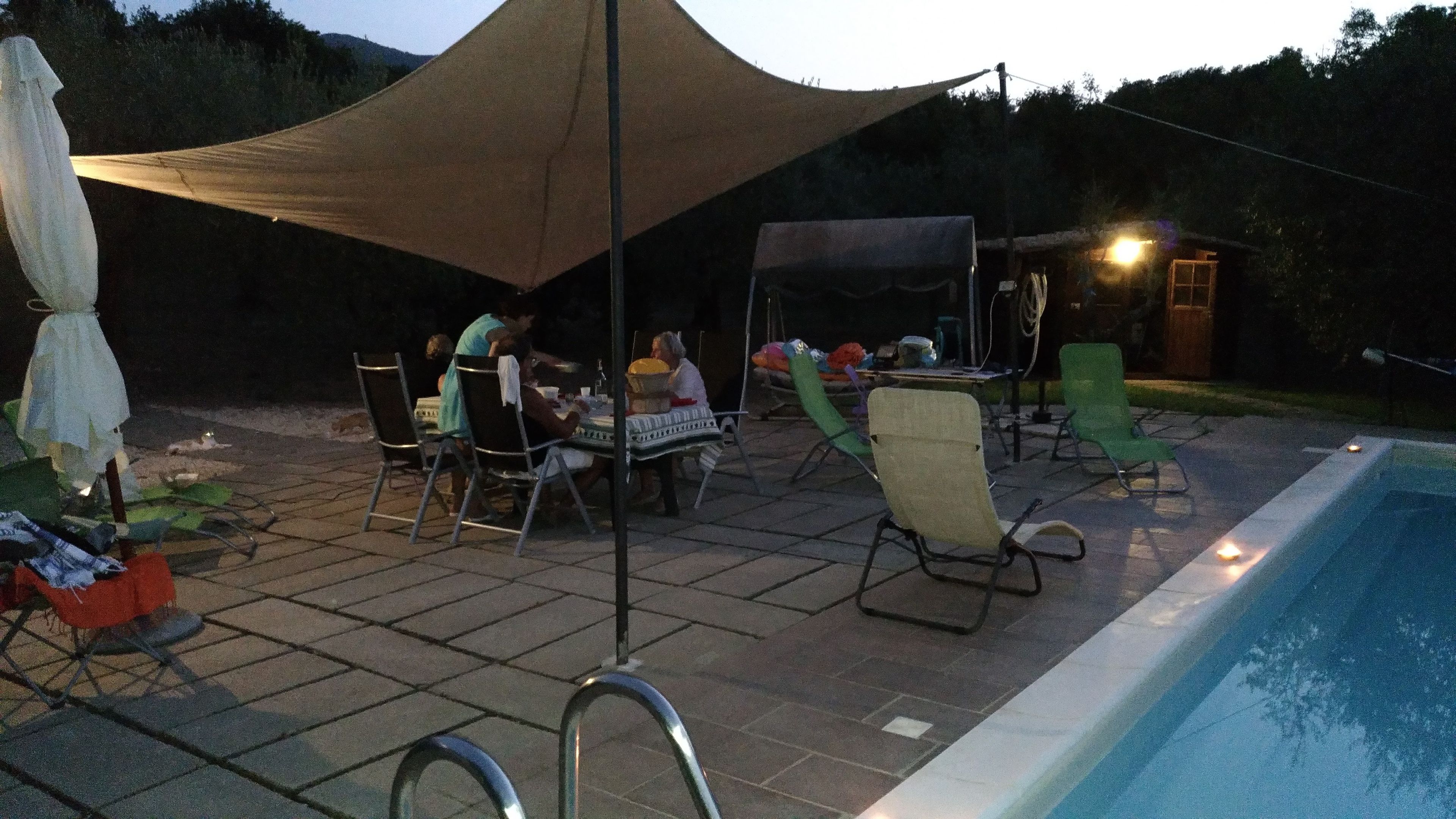 Eine Terrasse im Freien mit Tisch und Stühlen, einem Schwimmbad und einem Zelt, das Schatten spendet.