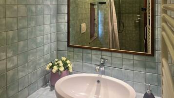 Un baño con un espejo grande, un lavamanos y una zona de ducha.