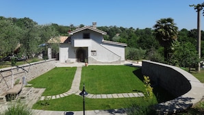 A building with a stone facade, a central entrance, and a surrounding lawn with a stone pathway. - Cà Fondi  (Lazio)