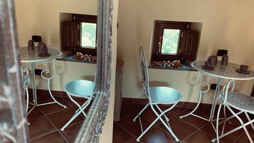 Una pequeña kitchenette con dos mesas redondas, sillas y una ventana.