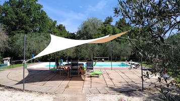 Un espace piscine doté d’un auvent, de chaises longues et d’une table.