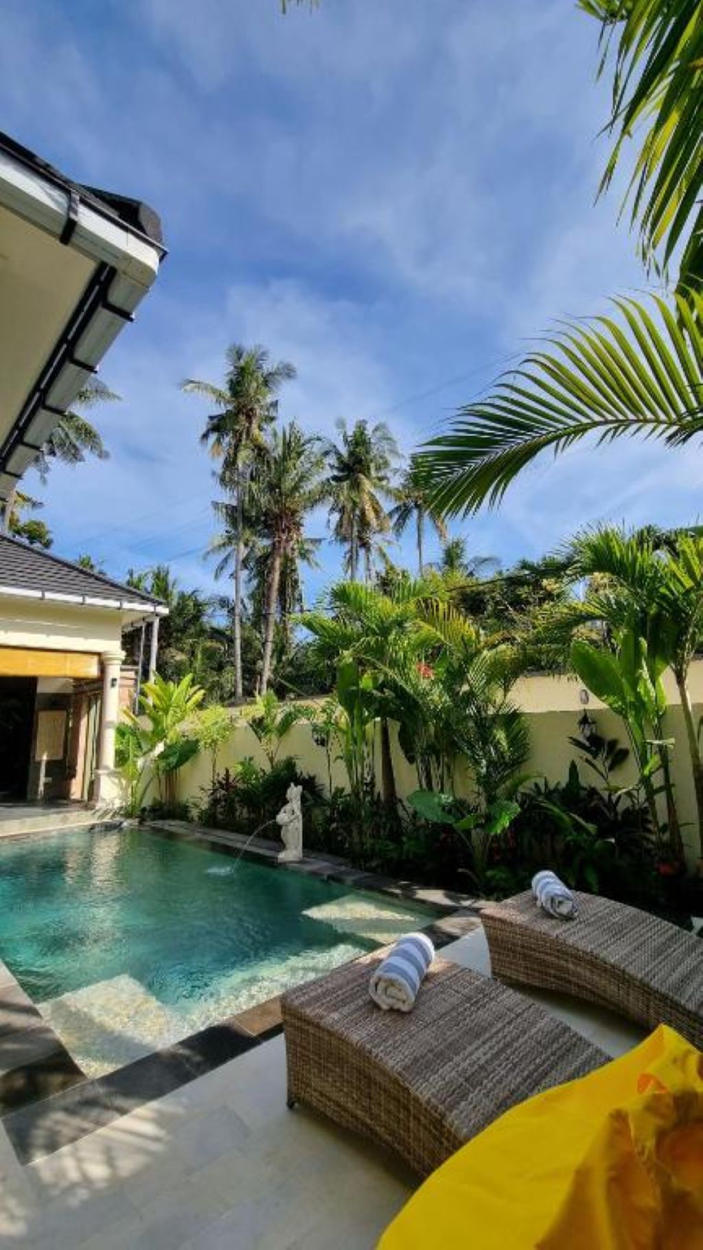 A swimming pool with lounge chairs and tropical plants.