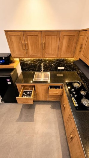 A compact kitchen with wooden cabinets, a black countertop, a sink, and a stove. - Charming Private Pool Villa in Lovina - Quiet Bali Escape (Buleleng)