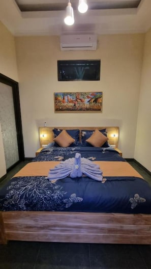 A bedroom with a bed, pillows, a painting, and an air conditioning unit. - Charming Private Pool Villa in Lovina - Quiet Bali Escape (Buleleng)