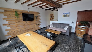 En modern inredning med en väggpanel av träribbor, en platt-TV, en grå soffa, ett träbord och en bardisk.