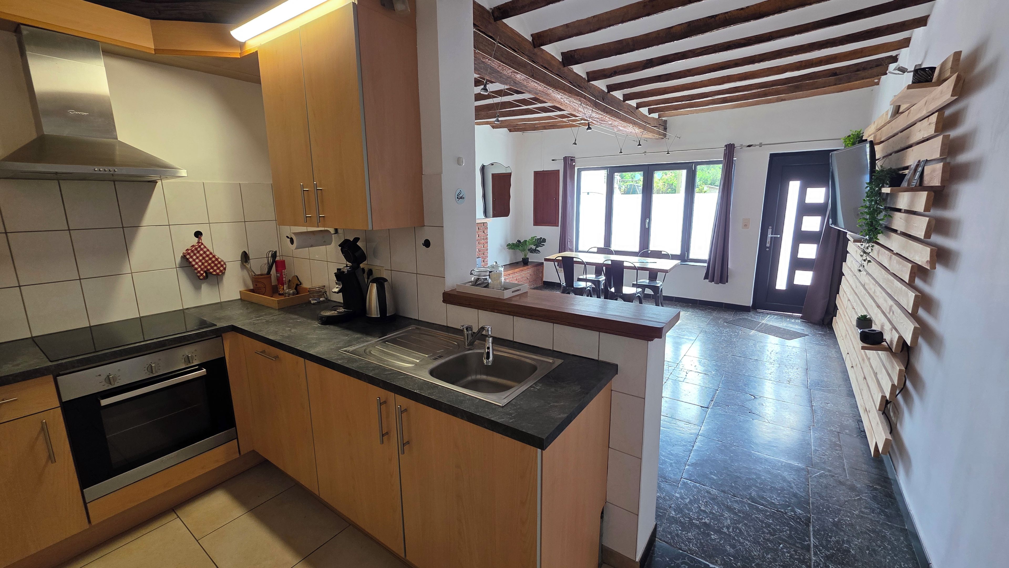 Cozinha moderna com armários de madeira, pia de aço inoxidável e forno embutido.