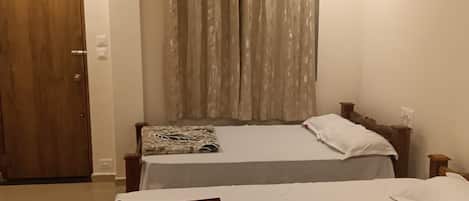 A hotel room with two beds, a ceiling fan, and a window with curtains.