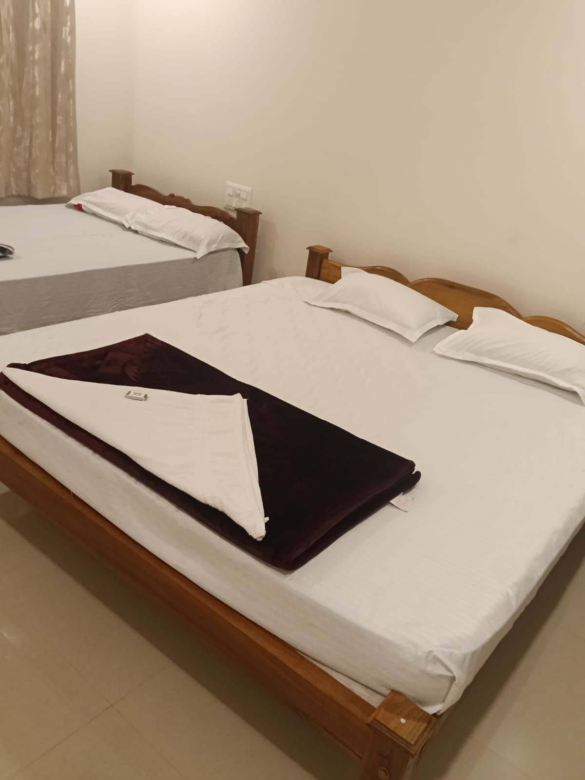 A room with two beds, each with wooden headboards and white bedding.