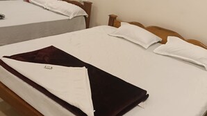 Una stanza con due letti, ognuno dotato di poggiatesta in legno e biancheria da letto bianca.