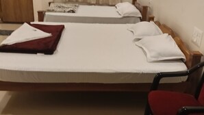 Ein Hotelzimmer mit zwei Betten, einem Holzschrank, einem roten Sessel und einem Vorhang.
