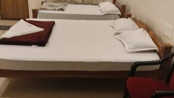 A hotel room with two beds, a wooden wardrobe, a red chair, and a curtain.