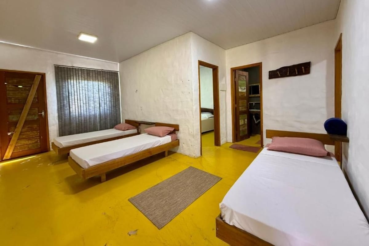 Una habitación con tres camas individuales, una puerta de madera y un espejo en la pared.