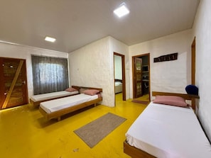 Una habitación con tres camas individuales, una puerta de madera y un espejo en la pared.