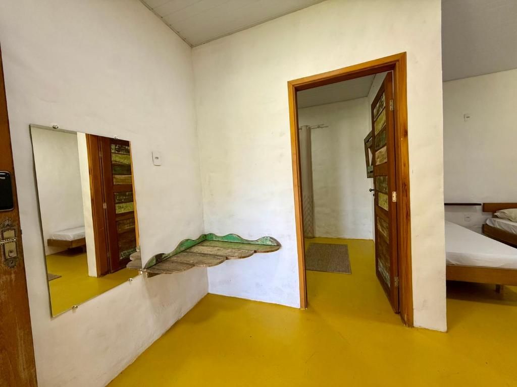 A room with a bed, a mirror, and a door leading to another room.