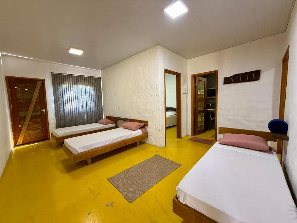 A room with two single beds, a wooden floor, and a white wall.