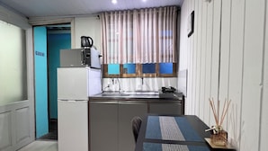 Cozinha compacta com geladeira, micro-ondas e cafeteira.