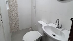 Um banheiro pequeno com vaso sanitário, pia e chuveiro.