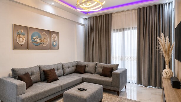 A modern living room with a sectional sofa, a coffee table, and a flat-screen TV on a wooden stand. - 2-bedroom 1A apartment in peaceful Dakar with AC, Sauna,WiFi and Fitness Room (Dakar)