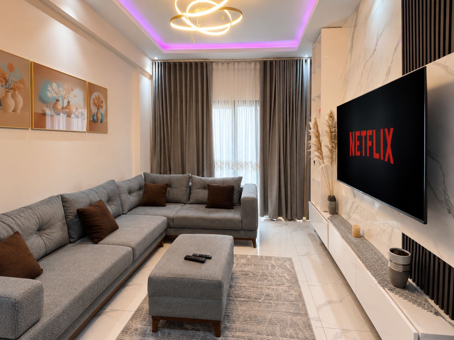 A modern living room with a sectional sofa, a flat-screen TV, and a decorative wall piece.