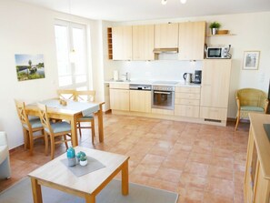 A modern kitchen with wooden cabinets, a built-in oven, and a microwave. - Apartment Building Linquenda 12 (Heringsdorf)