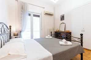 A hotel room with a bed, a dresser, an air conditioning unit, and a window with curtains. - Acropolis Classic Apartment (Athina)
