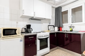 A compact kitchen with white cabinets, a stove, a microwave, and a coffee maker. - Acropolis Classic Apartment (Athina)