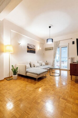 A modern living room with a sofa, a floor lamp, a painting, and a glass table. - Acropolis Classic Apartment (Athina)