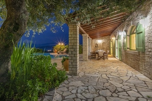 Un patio de piedra con mesa y sillas, una piscina y vistas a las montañas.