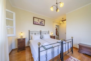 Un dormitorio con cama con dosel, mesitas de noche, una araña y un cuadro enmarcado en la pared.