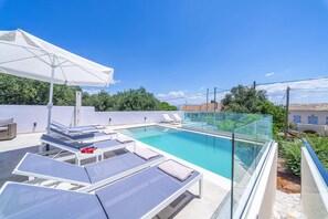 Piscina no terraço com espreguiçadeiras e estrutura de vidro.