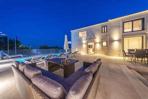 Ein Außenbereich mit Lounge-Möbeln und Pool, neben einem Gebäude mit Essbereich.