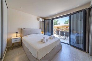 Ein Schlafzimmer mit Bett, Nachttisch und Blick auf eine Terrasse.