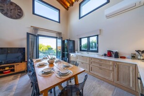 Cozinha moderna com área de refeições, janelas amplas e televisão integrada.