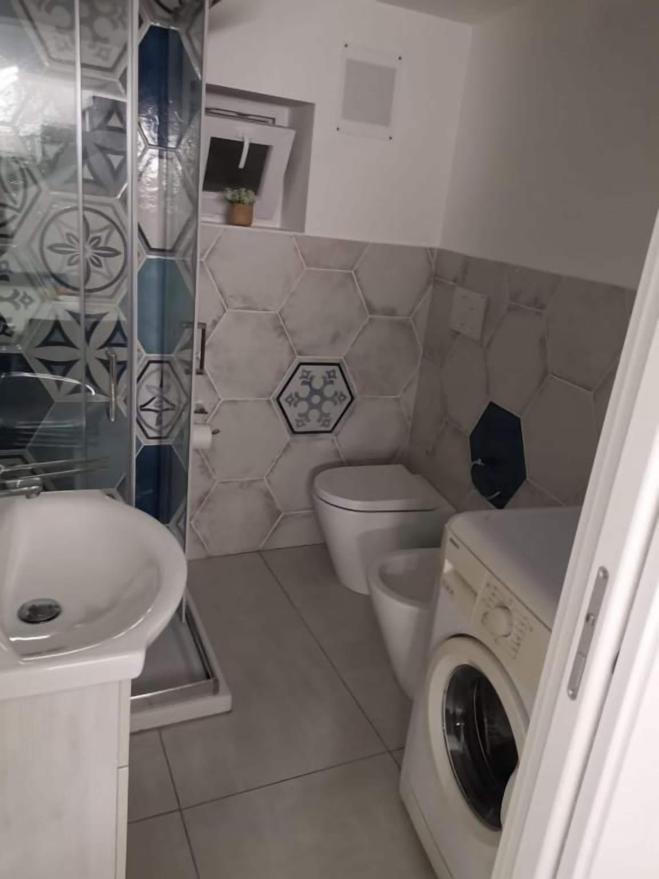 Une petite salle de bain comprenant un lavabo, des toilettes et un lave-linge.