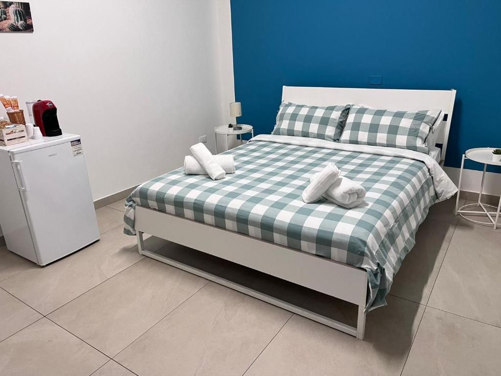 A hotel room with a bed, a small refrigerator, a nightstand, and a wall-mounted picture.