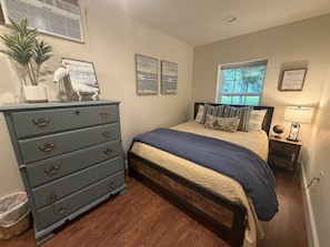 A bedroom with a bed, dresser, and window. - Just West of Little Rock Retreat (Paron)