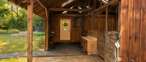 A wooden structure with a covered entrance, a door, and a bench outside.
