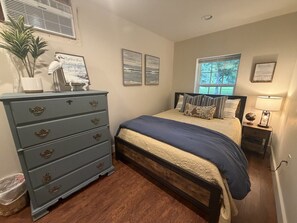 A bedroom with a bed, dresser, and window. - Barn Apartment | Peaceful Views | Just West of Little Rock (Paron)