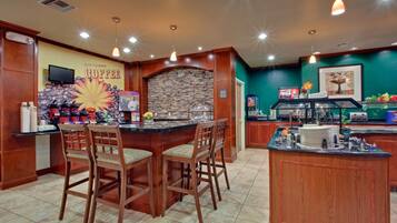A coffee shop with a stone wall, wooden bar, and bar stools.