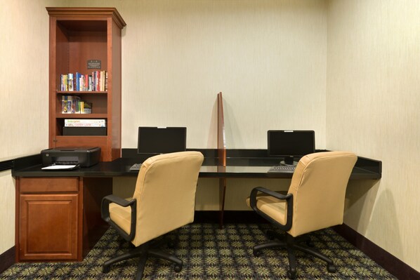 A conference room with two desks, chairs, a bookshelf, and a printer.
