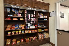 A snack, sundries, and candy section in a hotel lobby with various packaged goods and snacks.